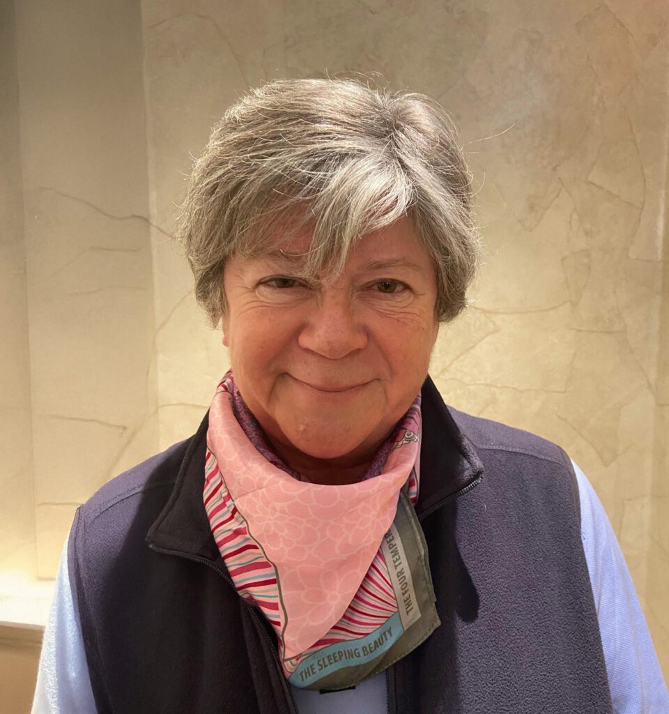Smiling older woman wearing a pink scarf.